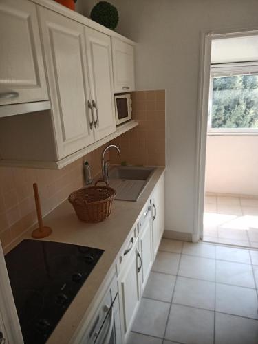 a kitchen with white cabinets and a sink and a microwave at T2 Terrasse vue mer in Six-Fours-les-Plages