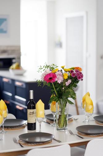 a table with a vase of flowers and a bottle of wine at 11 Breakwaters Way - Sandown in Sandown