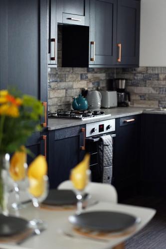 a kitchen with black cabinets and a table with dishes at 11 Breakwaters Way - Sandown in Sandown