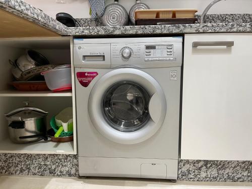 a washing machine in a kitchen under a counter at Très bel appartement à OLA BLANCA in Sidi Rahal