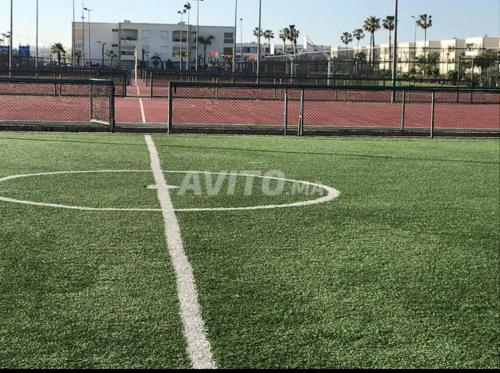 a tennis court with a white circle on a field at Très bel appartement à OLA BLANCA in Sidi Rahal