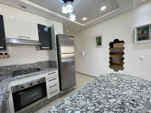 a kitchen with a stainless steel refrigerator and a stove at Très bel appartement à OLA BLANCA in Sidi Rahal
