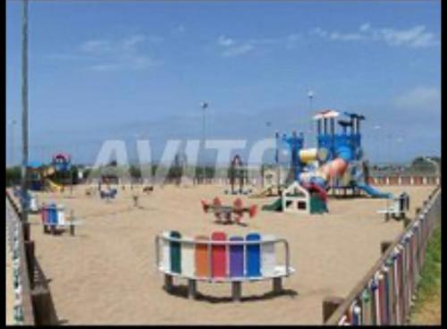 a beach with a playground with at Très bel appartement à OLA BLANCA in Sidi Rahal