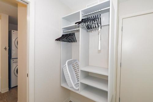 a walk in closet with white shelves and umbrellas at Parks Residential-Richardson in Richardson