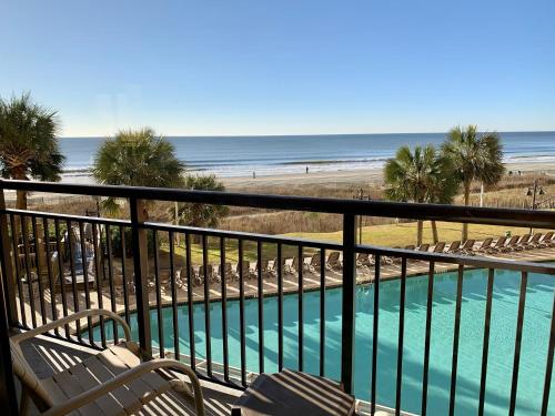 a balcony with chairs and a swimming pool and the beach at 210 Sea Gem Oceanfront Pet Friendly Oceanfront in Myrtle Beach
