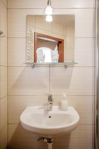 a white sink in a bathroom with a mirror at Guest House "Arkhistratyg" in Lviv