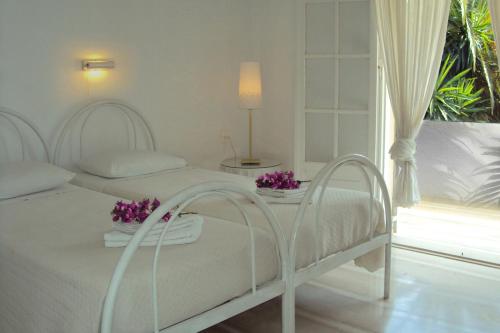 a white bedroom with two beds and a window at Maison Metel in Kontokali