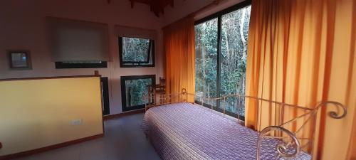 1 dormitorio con cama y ventana grande en Cabañas Bosque Encantado en Merlo