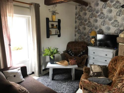 a living room with a couch and a tv at Gite de la Huberderie in Quettehou