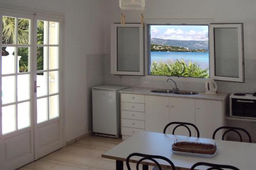 a kitchen with white cabinets and a table with chairs at Maison Metel in Kontokali