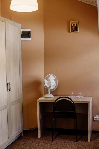 a room with a desk with a fan and a chair at Guest House "Arkhistratyg" in Lviv
