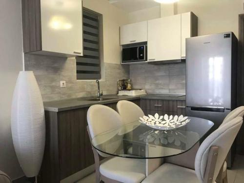 a kitchen with a glass table and white chairs at Colibri Luxury Apartments in Hanioti