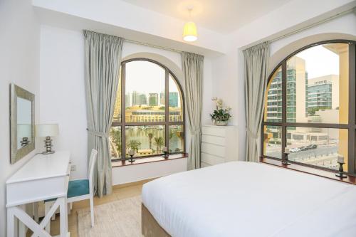 a bedroom with a bed and a desk and two windows at Dubai, Lux apartment on JBR, 1BR, beach, pool, parking in Dubai