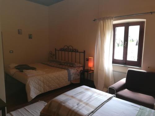 a bedroom with two beds and a chair and a window at CASALE SAN FORTUNATO in Spello