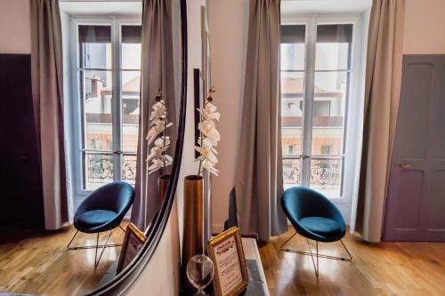 une chambre avec deux chaises bleues et un miroir dans l'établissement L'Idéal - 2 pièces en hypercentre, à Annecy