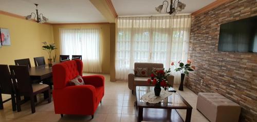 a living room with red chairs and a brick wall at Departamento Jireh in Tarija