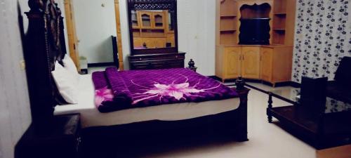 a bedroom with a bed with a purple blanket at Butt Lodges 3 in Islamabad