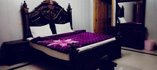 a bedroom with a bed with a purple comforter at Butt Lodges 3 in Islamabad