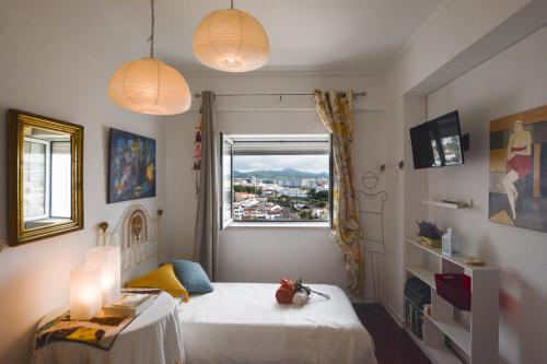 ein Schlafzimmer mit einem Bett, einem Fenster und zwei Lampen in der Unterkunft Marina Tower Center in Ponta Delgada