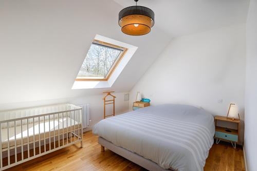 a white bedroom with a crib and a window at Maison Bourg idéale familles in Baden