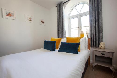 a bedroom with a white bed with yellow and blue pillows at The Old Chapel Leyburn in Leyburn