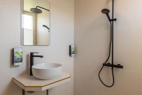 La salle de bains est pourvue d'un lavabo et d'une douche. dans l'établissement The Originals Boutique, Hôtel Porte de Dieppe, à Saint-Aubin-sur-Scie