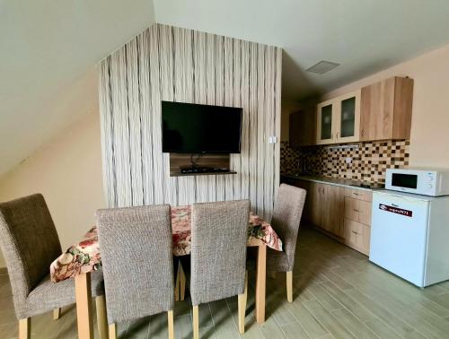 a kitchen with a table with chairs and a television on a wall at Székely Ház in Sopron