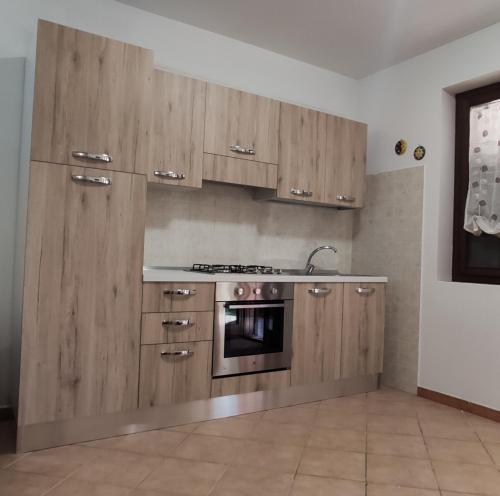 a kitchen with wooden cabinets and a stove top oven at Kiterhouse in Case Milazzo