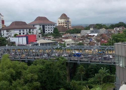 ein Zug, der eine Brücke über eine Stadt mit Verkehr überquert, in der Unterkunft Apartemen Malang in Malang