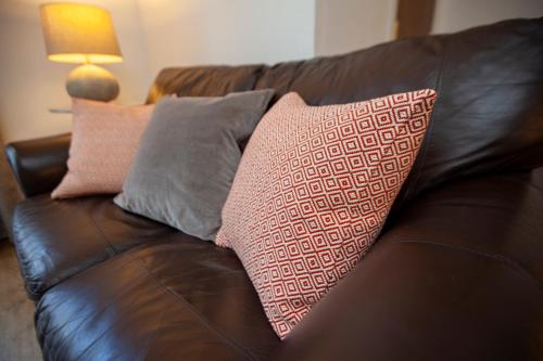 a brown leather couch with pillows on it at The Old Chapel Leyburn in Leyburn