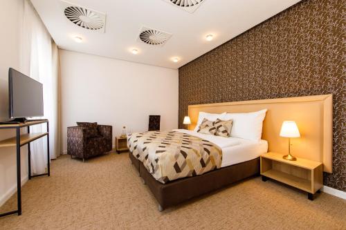 a bedroom with a bed and a flat screen tv at BEIGLI Hotel & Garden in Bratislava