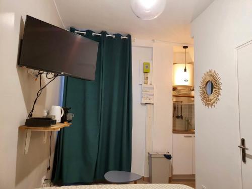 Cette chambre dispose d'un rideau vert et d'une télévision à écran plat. dans l'établissement Home Sweet Home Sacré-Coeur Montmartre, à Paris