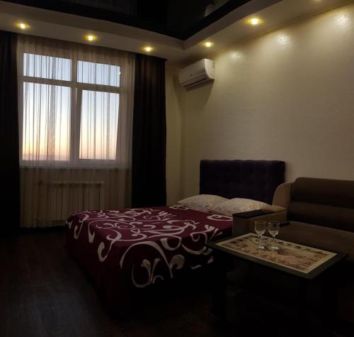 a bedroom with a bed and a couch and a window at Апартаменты на 25 этаже. in Kharkiv
