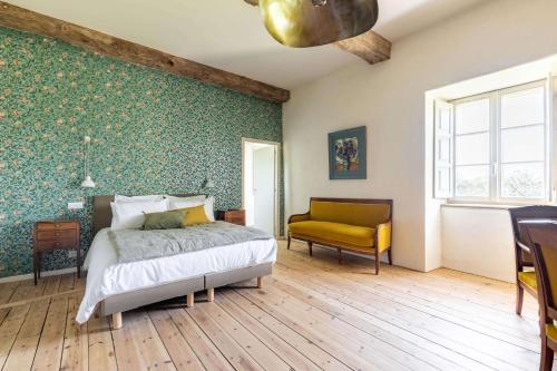 a bedroom with a bed and a yellow chair at Manoir du Guern in Pluvigner