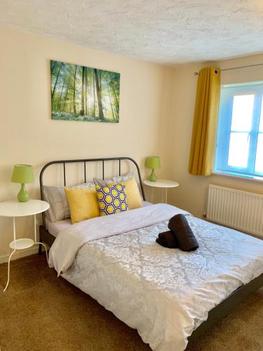 a bedroom with a bed with two tables and a window at Cosy Corner House in Kettering