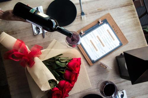 a table with roses and a bottle of wine and a glass at Maja Hotel Boutique in Morelia