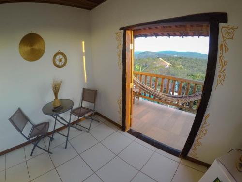 Habitación con balcón con mesa y sillas. en Topo do Cipó Ecopousada Vegana, en Serra do Cipo