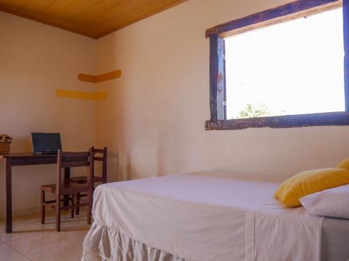 a bedroom with a bed and a desk and a window at Topo do Cipó Ecopousada Vegana in Serra do Cipo