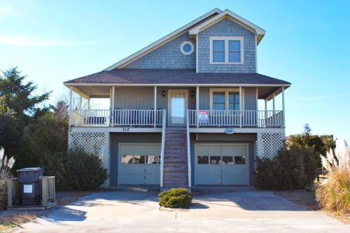 a house with a balcony and two garage doors at The Owen-ly Place to Be in Holden Beach