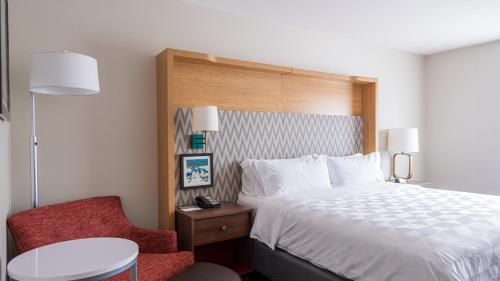 a hotel room with a bed and a chair at Holiday Inn & Suites Philadelphia W - Drexel Hill by IHG in Drexel Hill