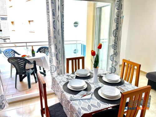 a dining room table with plates and flowers on it at APARTBEACH GOLDEN I MUY LUMINOSO JUNTO PLAYA y CLIMATIZADO in Salou