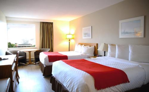 a hotel room with two beds and a desk at Auberge du Grand Lac in Magog-Orford