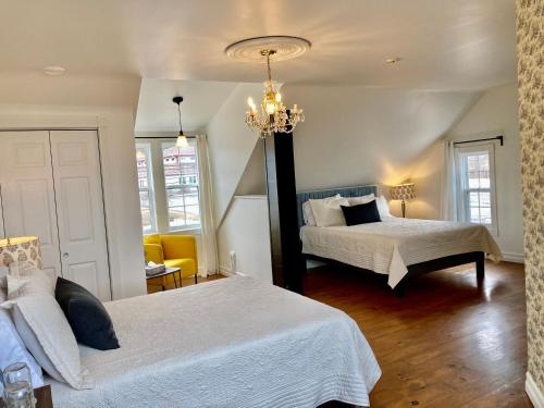a bedroom with two beds and a chandelier at Groundswell Pub & Inn in DʼEscousse