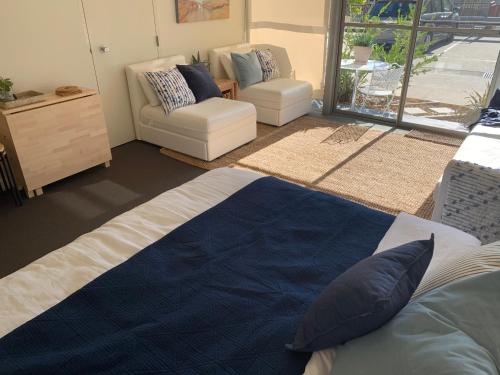 a bedroom with a bed and a chair and a window at Lorne Studio Apartment in Lorne