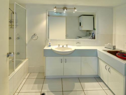 a white bathroom with a sink and a mirror at Mainsail 3 in Mooloolaba
