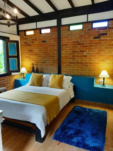 a bedroom with a large bed with a brick wall at Hotel Vísperas in Santa Rosa de Cabal