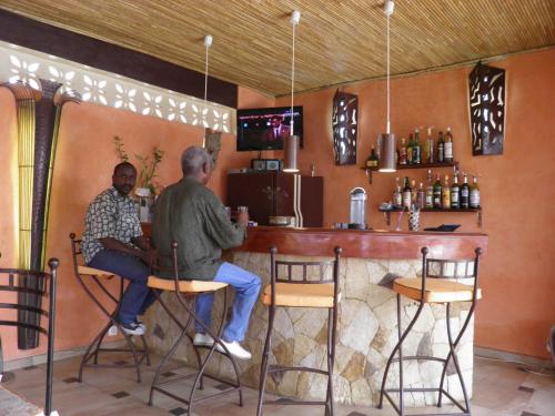 two men sitting at a bar in a restaurant at Le Dakan in Saly Portudal
