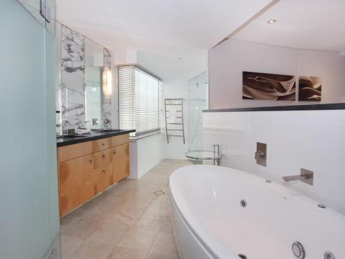 a white bathroom with a tub and a sink at Oceans 201 luxurious beachfront apartment in Mooloolaba