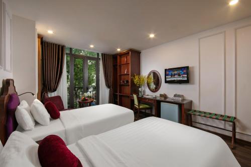a hotel room with two beds and a desk at Vision Premier Hotel & Spa in Hanoi