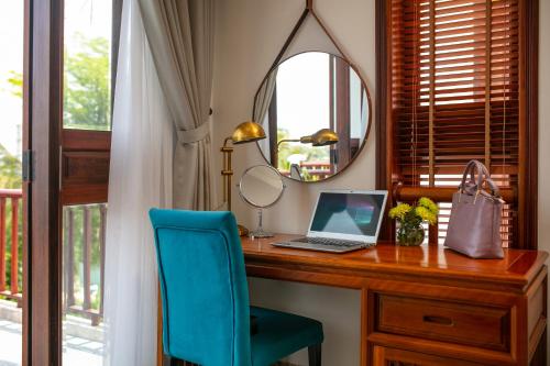 a desk with a laptop and a blue chair at Hoi An Riverside Villas & Apartments in Hoi An